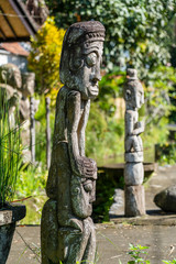 Balinese ancient wooden statue on street in Ubud, island Bali, Indonesia. These figures of the gods protect the house from evil spirits