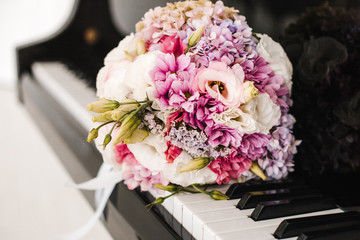 a bouquet of pink, white and yellow flowers lies on the keys of the piano