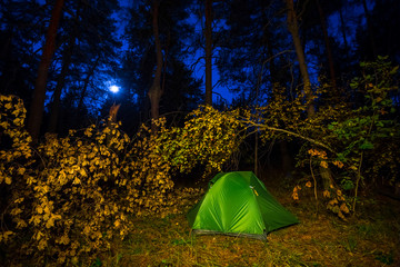 night touristic camp scene, green touristic tent in a autumn forest at the night