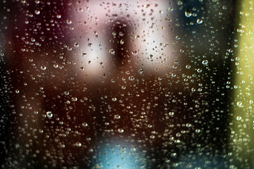 Wet blue glass. Colored blurred background. Evening rain. Misted glass.