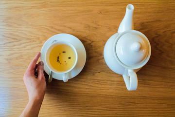 White teapot and white net, green leaf tea on a wooden background.