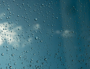 Blue sky through wet glass. Raindrops on glass. Misted glass.