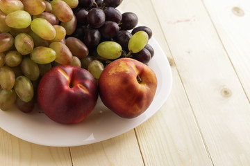 Tasty ripe fruits on plate, on wooden table
