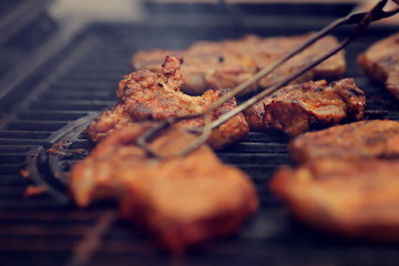 closeup on crispy grilled meat that is grilled on hot cast-iron grate - realistic food and barbecue party concept - foreground and background blanked out blurry
