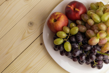 Tasty ripe fruits on plate, on wooden table