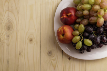 Tasty ripe fruits on plate, on wooden table