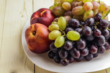 Tasty ripe fruits on plate, on wooden table
