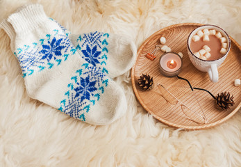 Cozy autumn or winter composition with knitted socks, candles and cocoa with marshmallows