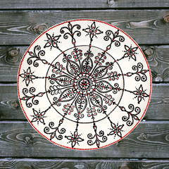 Decorative ceramic plate, hand painted dot pattern with acrylic paints on a gray wooden background. A square photo. Closeup.