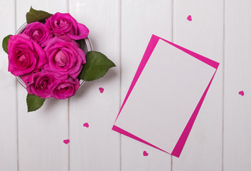 Mock-up with pink roses and small paper hearts on the white wooden table, top view