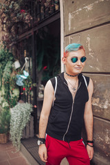 Homosexual male with stylish hairstyle and gay glasses posing at flowers boutique on background