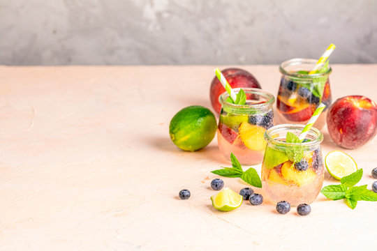 Blueberry and peach infused water, cocktail, lemonade or tea. Summer iced cold drink with blueberry, lime, peach and mint.