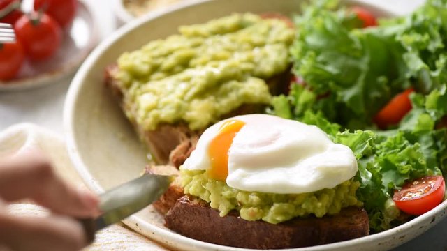 Poached egg on rye bread toast with avocado and green leaf salad kale. Healthy food, clean eating concept. Closeup