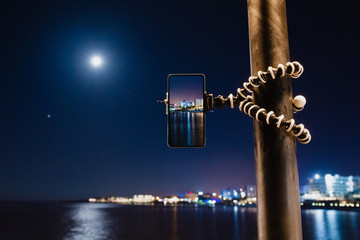 Using smartphone on flexible tripod to making the photo of sea night landscape