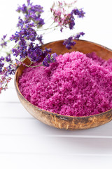 Sea salt in bowl, aroma oil in bottles, Wellness and flowers on grey textured background and flowers on vintage wooden background. Selective focus.