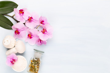 Sea salt, aromatherapy oil in bottles and orchid on vintage wooden background.