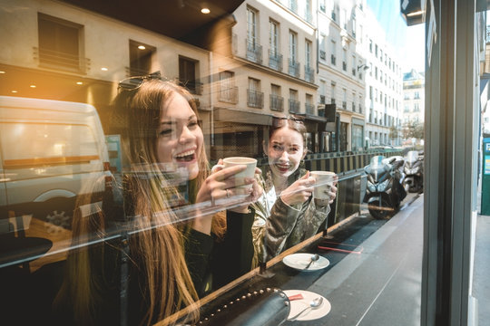 You always make me laugh. Best friend girls sitting at caffee and smiling while talking to each other.