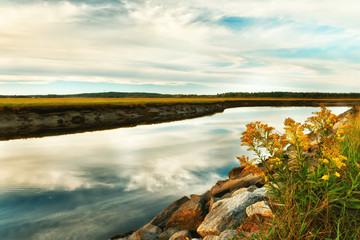River, swampy terrain, straits from the ocean. autumn landscape. Twilight, long exposure. Cloud movement. USA. Maine.