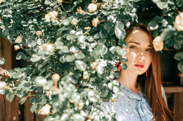 Fashion portrait of young brunette female model in the bushes