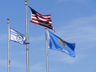 Wide shot of the flags of the United States, Oklahoma State and Little Axe School in Oklahoma