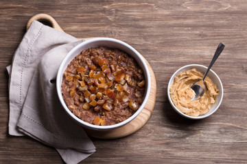 Delicious oatmeal in a white bowl, dates fruits and cocoa. healthy breakfast on a wooden background	