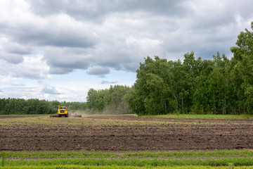 Ploughing Tractor At Field Cultivation Work. machine plows the field, harrows and cultivates the...