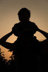Silhouettes of young mother with baby daughter playing