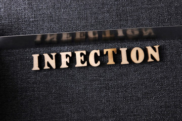 The word infection on the table of the wooden letters of the English alphabet with . Designer concept to describe the problem, the danger of mass infection in the world.