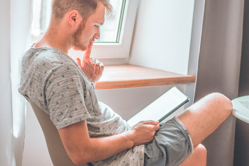 Technology, home - lifestyle concept close up of man working with the tablet computer and sitting on chair at home