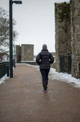 Woman walking away on city walls in snow