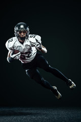 American football sportsman player in helmet isolated on black background. Sport and motivation...