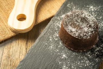 Chocolate fondant with icing sugars on top, on a black slate plate, selective focus