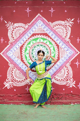 Indian classical odissi dancer posing infront of wall Street Art (Pattachitra) at Bhubaneswar, Odisha, India 