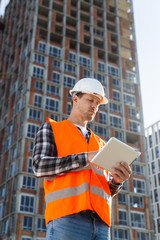 Medium shot low angle view construction engineer looking at tablet