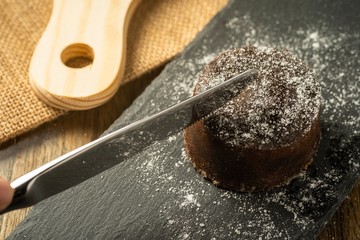 Chocolate fondant with icing sugars on top, on a black slate plate, selective focus