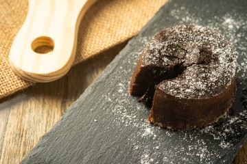 Chocolate fondant with icing sugars on top, on a black slate plate, selective focus