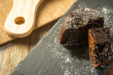 Chocolate fondant with icing sugars on top, on a black slate plate, selective focus