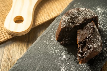 Chocolate fondant with icing sugars on top, on a black slate plate, selective focus