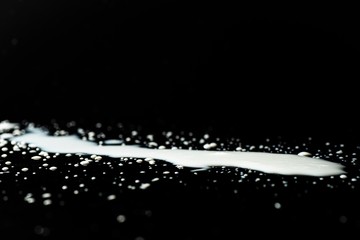 Milk spilled on black surface, closed up, selective focus