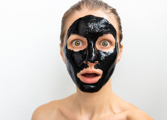 Humorous emotional young woman portrait with black mask on her face. Funny beauty spa treatment 