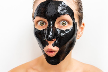 Humorous emotional young woman portrait with black mask on her face. Funny beauty spa treatment 