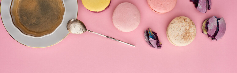 top view of delicious French macaroons near coffee on pink background, panoramic shot