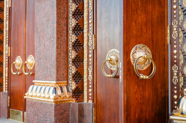 Ancient wooden gate with two door knocker rings close-up side view. Old Door Fragment of Buddhist temple Datsan Gunzechoyney.