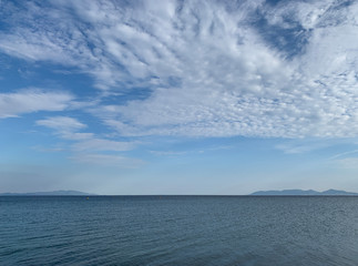 Cloudy blue and white sky above of blue sea.