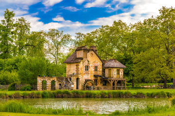 Picturesque view of the Mill, a rustic building in the Queen's Hamlet, surrounded by trees under a...