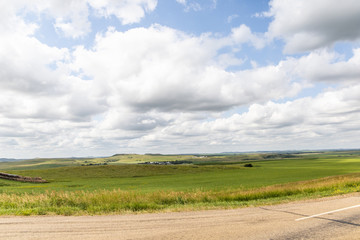 Fototapeta premium a long dirt road in rural North Dakota with a bright blue sky with clouds in the horizon