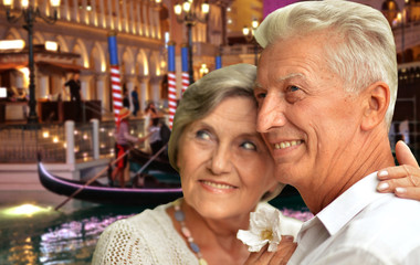Portrait of happy senior couple posing against blurred cityscape background