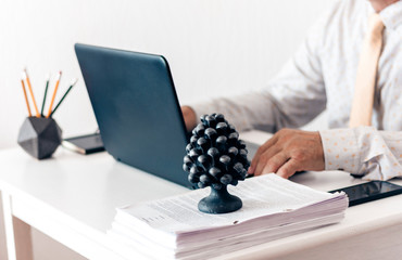 man  on keyboard laptop computer, concrete holder with pencils and pens, notebook, smartphone, glasses and black paperweight on white table, education office concept backgroundю
