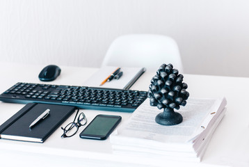 modern workplace: keyboard laptop computer, concrete holder with pencils and pens, notebook, smartphone, glasses, stack of documents and black paperweight, education office concept background.