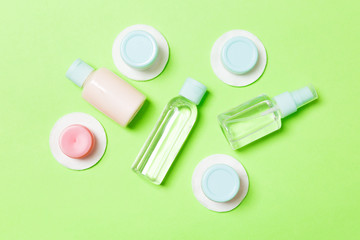 Group of small bottles for travelling on green background. Copy space for your ideas. Flat lay composition of cosmetic products. Top view of cream containers with cotton pads